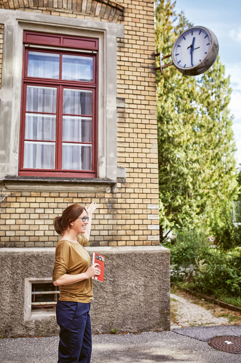 Eine Stadtführerin vor einem alten Backsteinhaus und einer Uhr